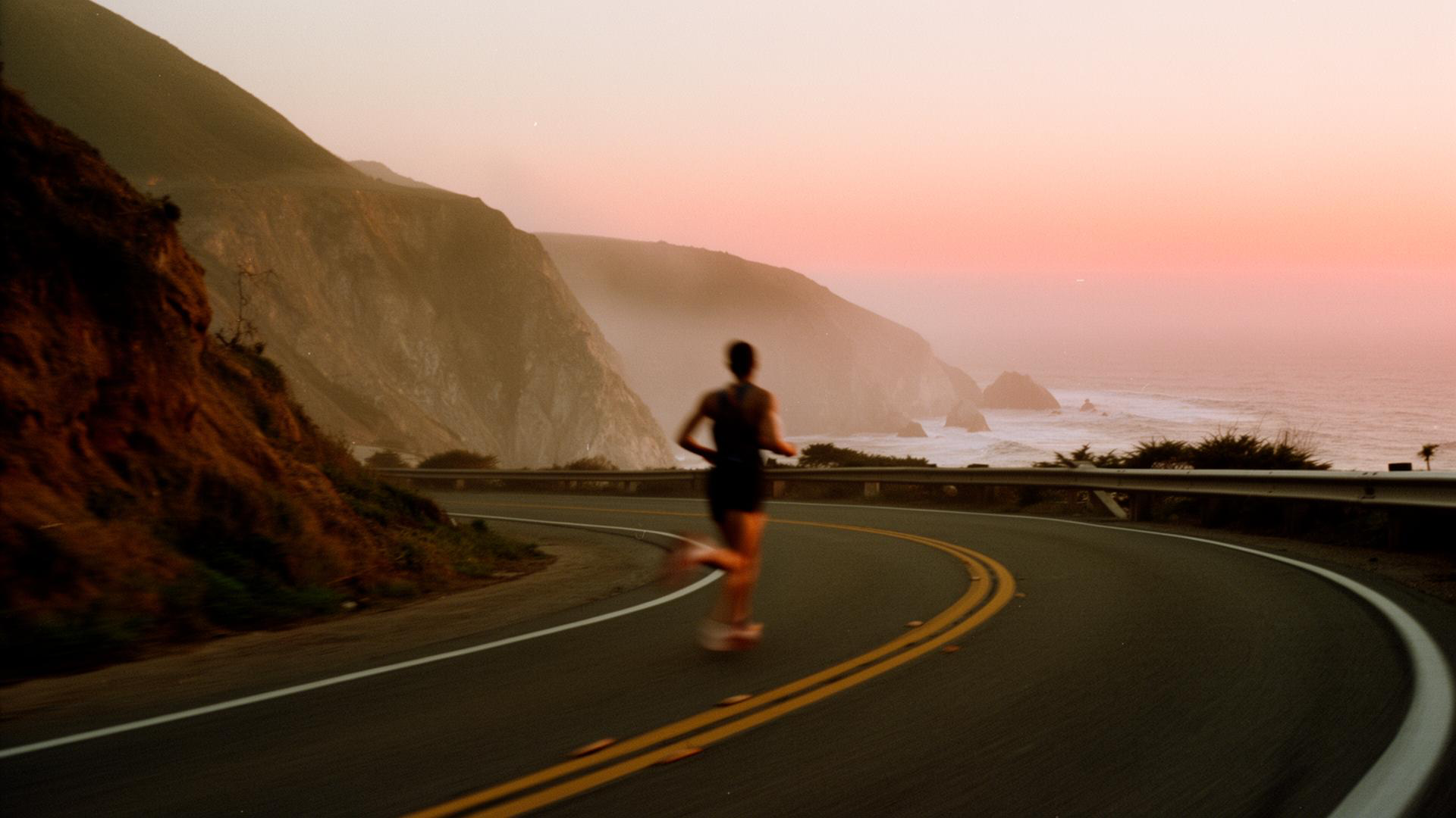 Runner on a coastal cliffside road at golden hour